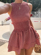 Woman wearing the Modarine gingham smocked drop-waist mini dress